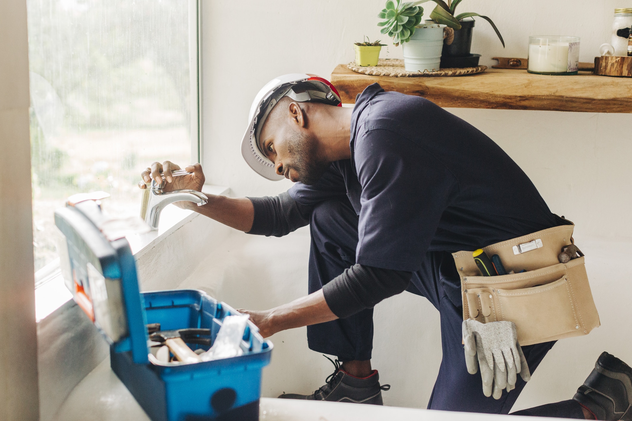 Plumber fixing a leaking bathroom faucet